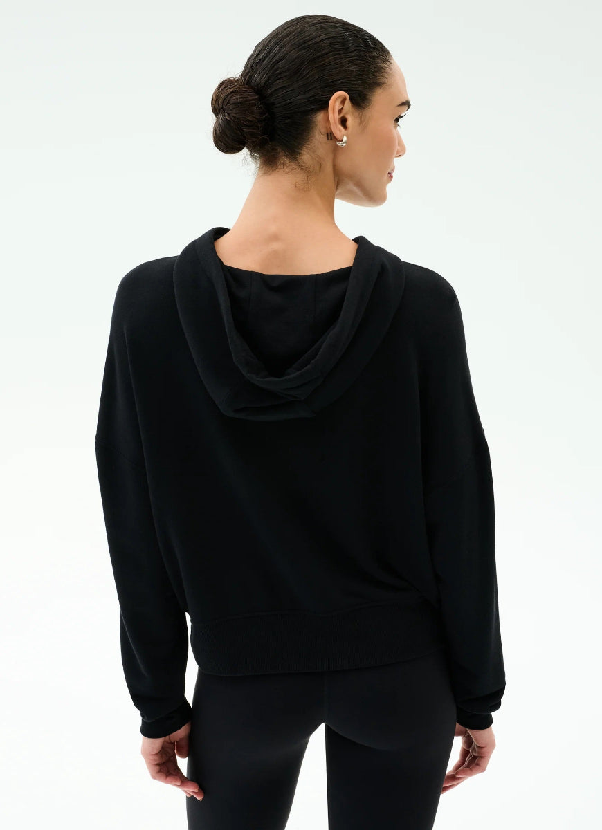 Woman wearing a black hoodie and pants on a white background