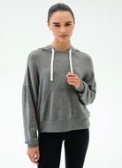 Woman wearing a gray hoodie with white drawstrings on a white background