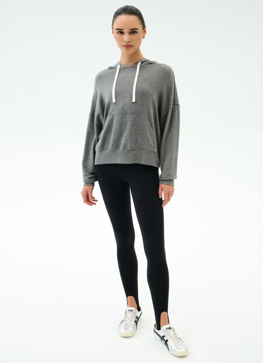 Woman wearing a gray hoodie and black leggings on a white background