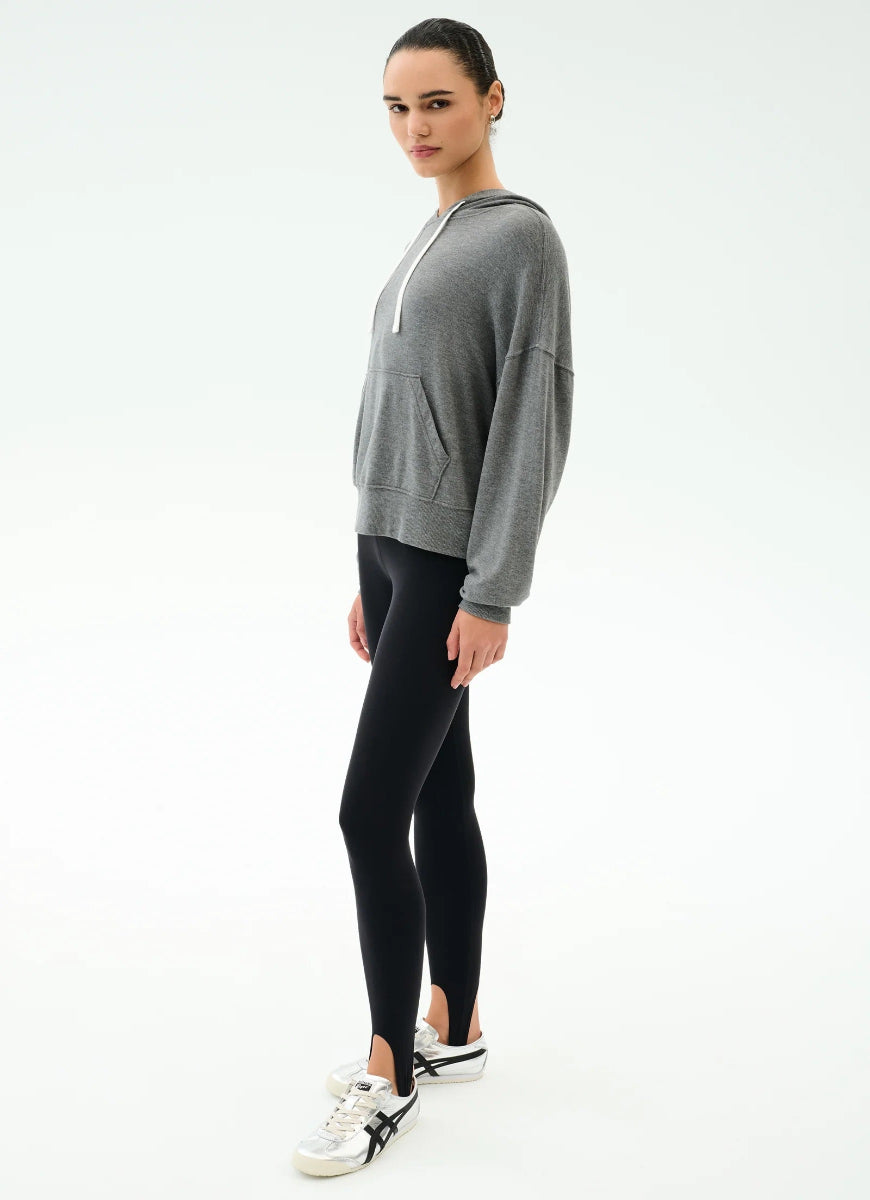 Woman wearing a gray hoodie and black leggings on a white background