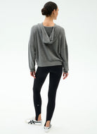 Person wearing a gray hoodie and black leggings on a white background