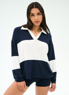 Woman wearing a navy and white color-blocked sweater on a plain background