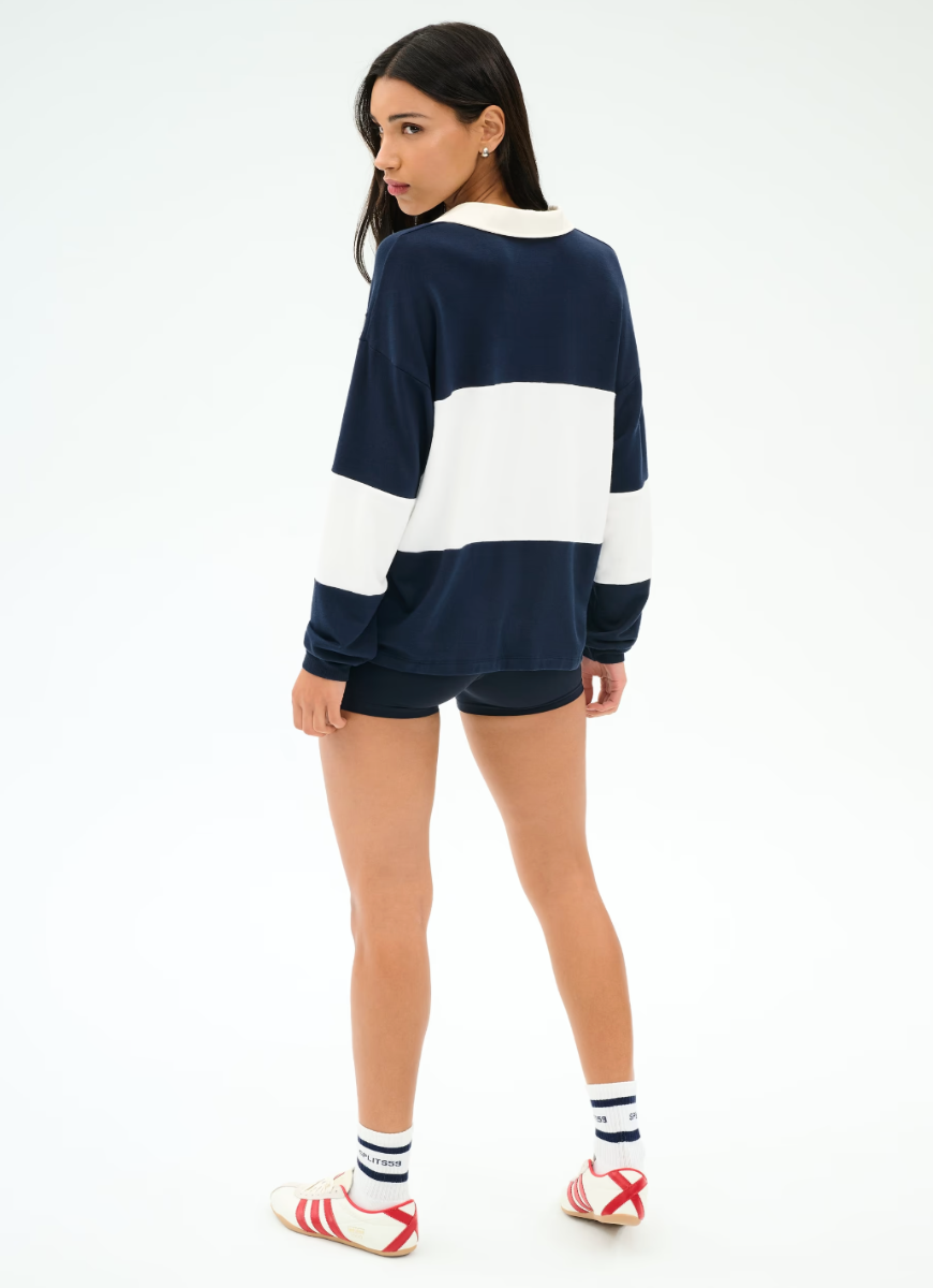 Woman wearing a navy and white striped sweater with shorts on a white background