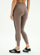 Beige leggings with a side stripe worn by a person on a white background