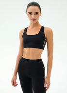 Woman wearing a black sports bra and leggings on a white background