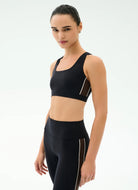 Woman wearing a black sports bra and leggings on a white background