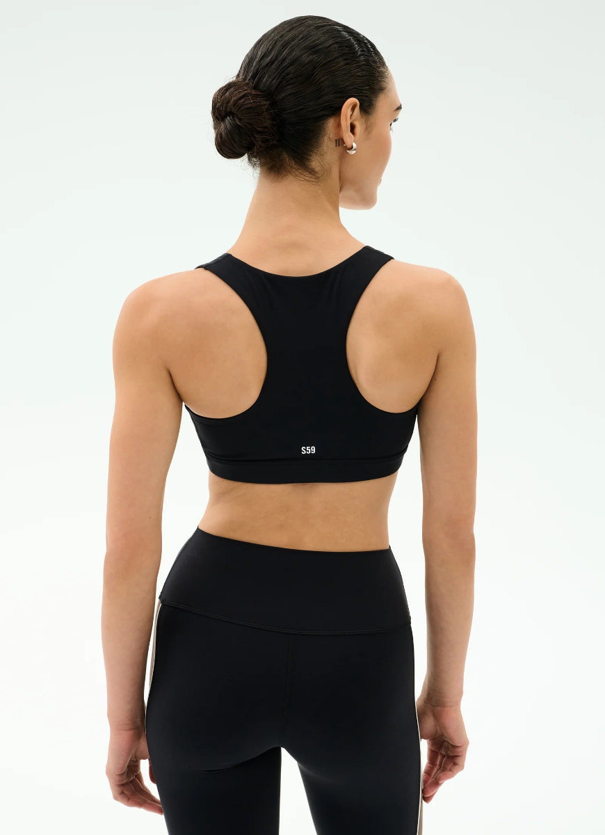 Woman wearing a black sports bra and leggings on a white background