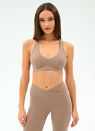 Woman wearing a beige sports bra and leggings on a white background