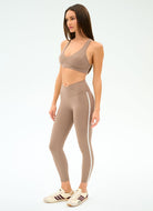 Woman wearing a beige sports bra and leggings set on a white background