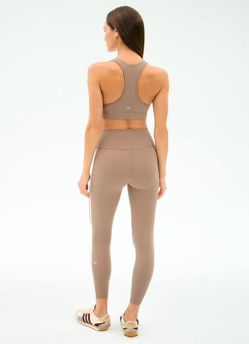 Woman wearing a beige sports bra and leggings set on a white background