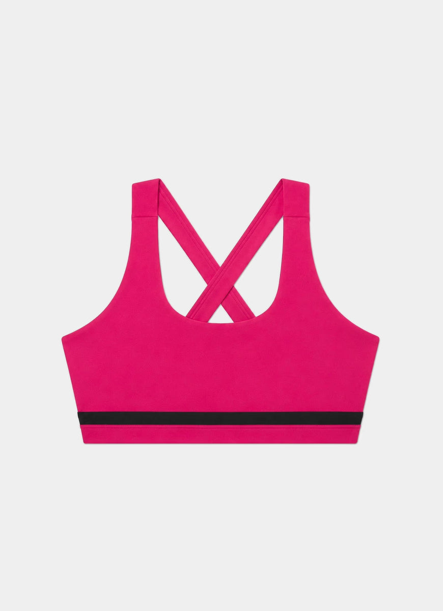 A bright pink sports bra with a black horizontal stripe across the underband and crisscross straps at the back, shown flat on a light gray background.