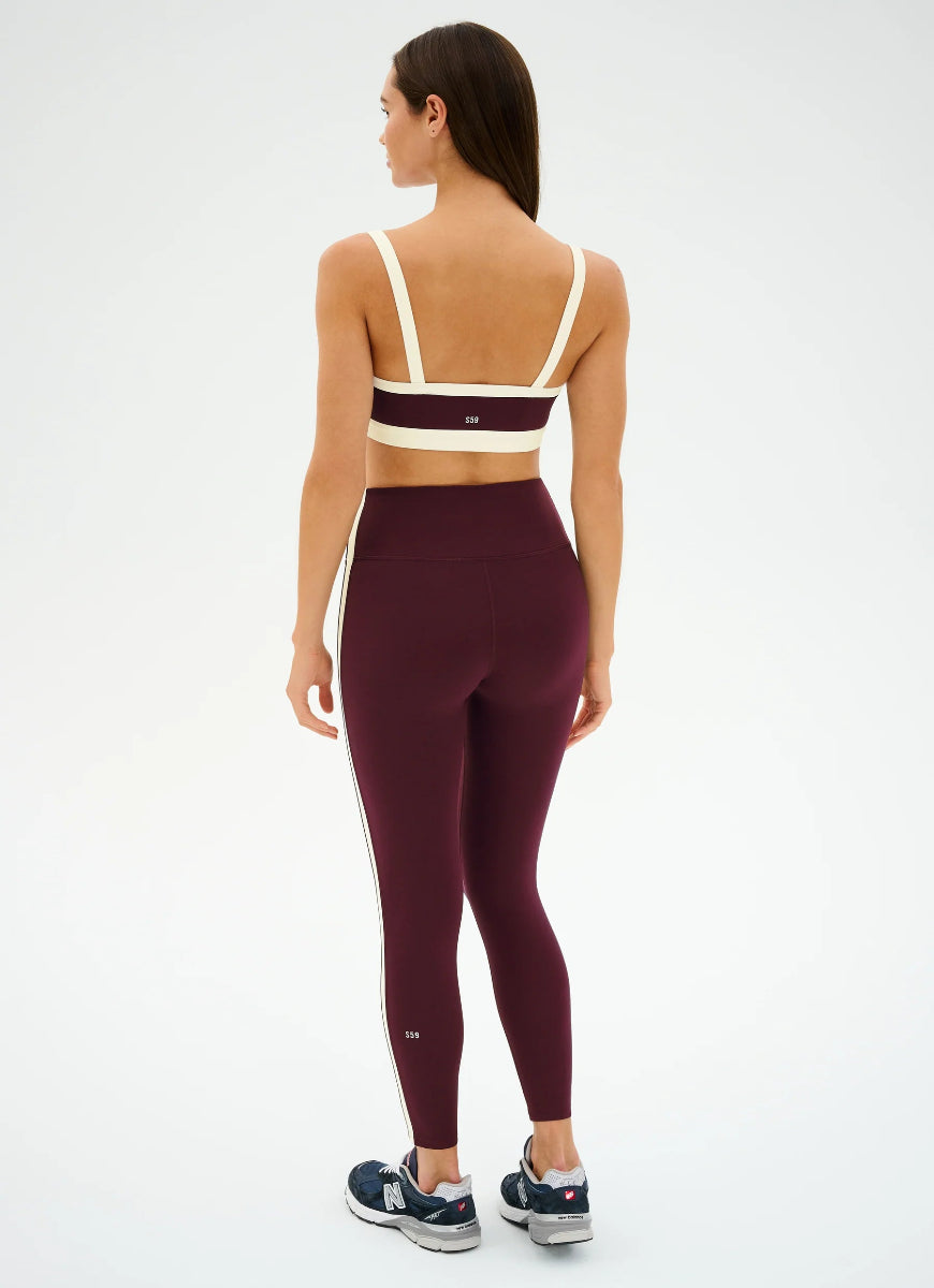 Woman wearing a burgundy sports bra and leggings set on a white background
