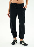 Person wearing black jogger pants with a white background