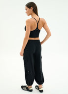 Woman wearing a black sports bra and cargo jogger pants on a white background