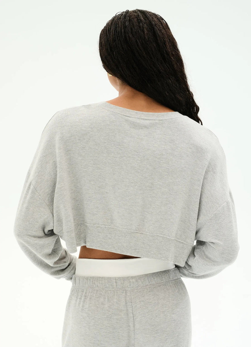A woman shown from the back wearing a light heather gray cropped sweatshirt and matching gray sweatpants against a plain white studio background.