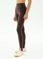 Person wearing brown leggings with a white background