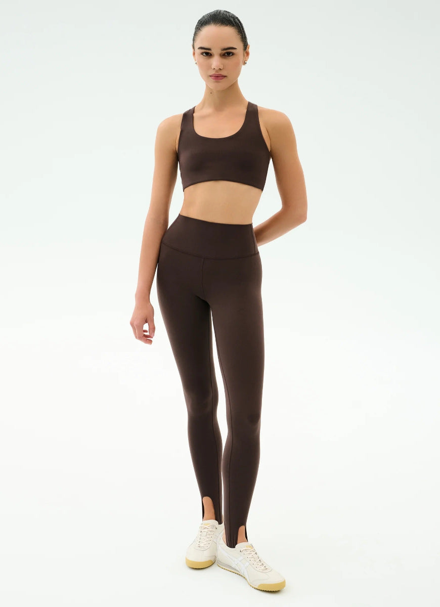 Woman wearing a brown sports bra and leggings set on a white background