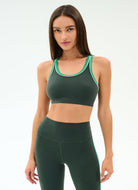 Woman wearing a green sports bra and leggings set on a white background