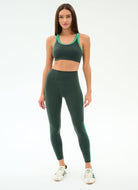 Woman wearing a green sports bra and leggings set on a white background
