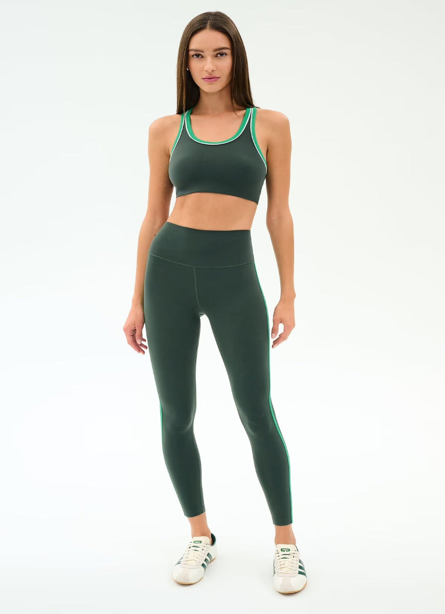 Woman wearing a green sports bra and leggings set on a white background