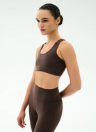 Woman wearing a brown sports bra and leggings on a white background