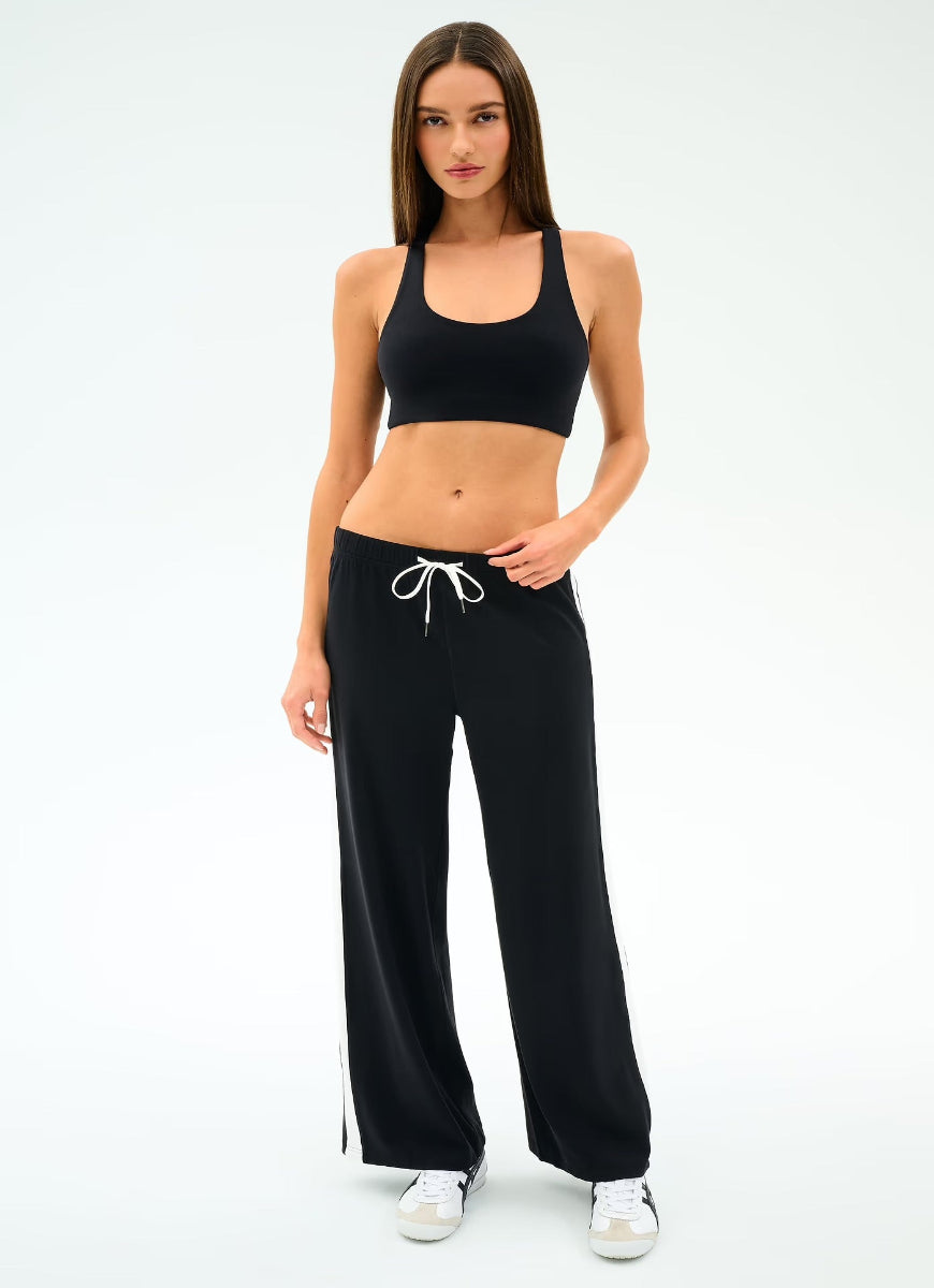 Woman wearing a black sports bra and black pants on a white background