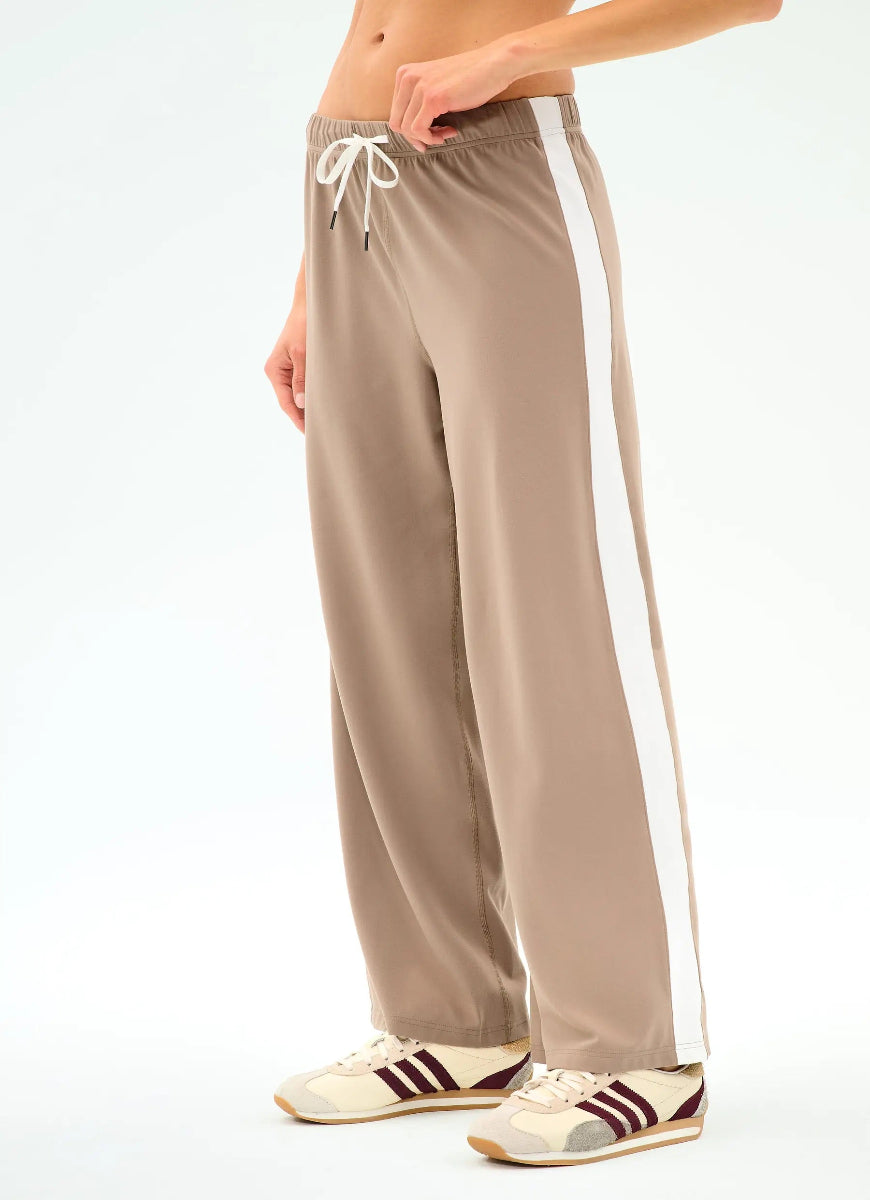 Beige sweatpants with a white stripe on a plain background