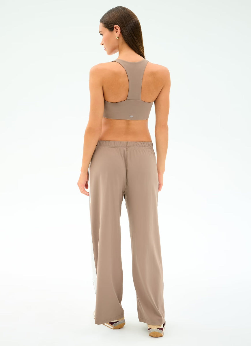 Woman wearing a beige sports bra and pants on a white background