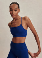Varley Assure Cerys Sports Bra in Sodalite Blue Front View With Model in a Stretching Pose