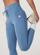 Vuori Daily Pocket Legging in Light French Blue Model in a Stretching Pose