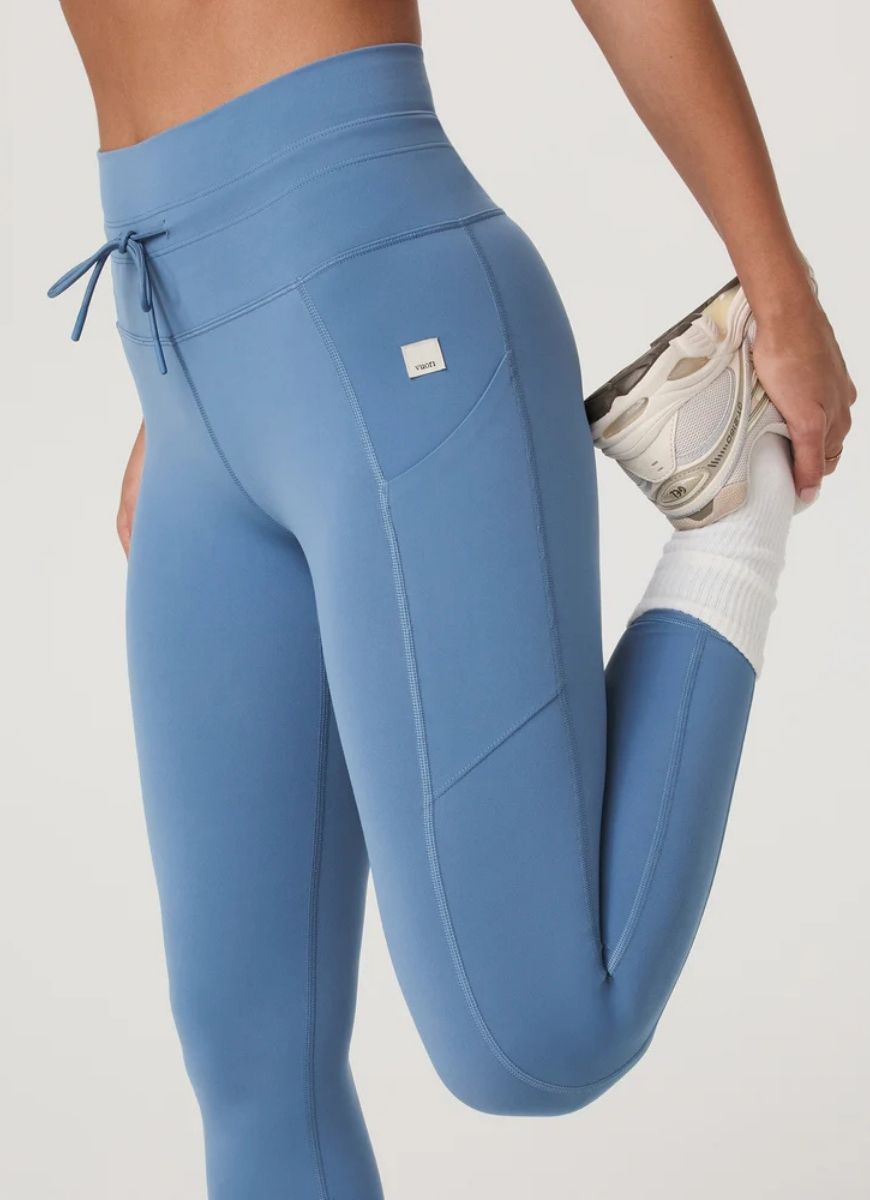 Vuori Daily Pocket Legging in Light French Blue Model in a Stretching Pose