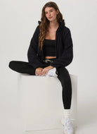 Vuori Women's Performance Jogger Long in Black Heather Front View With Model Sitting Down