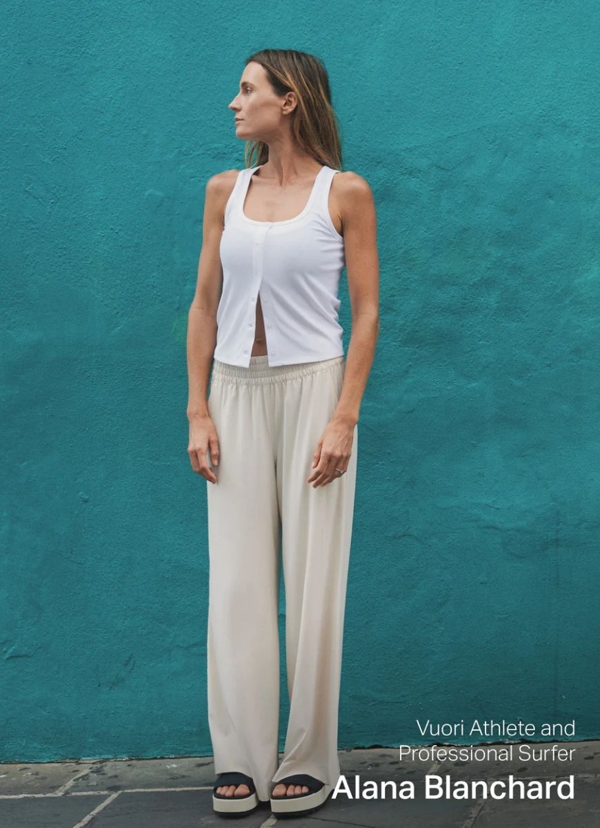 Vuori Villa Wideleg Pant in Milkweed Front View With Model Standing in Front of a Green Wall