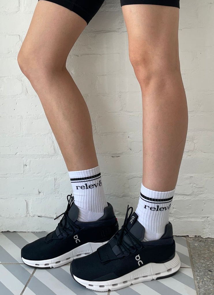 relevé Crew Socks in White with Black Logo Model Wearing Black Running Shoes