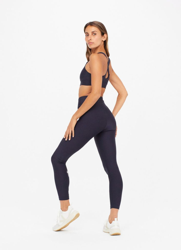 The Upside Matte Tech Midi Women's Pant in Indigo Full Model Side Pose with Model Looking Over her Shoulder