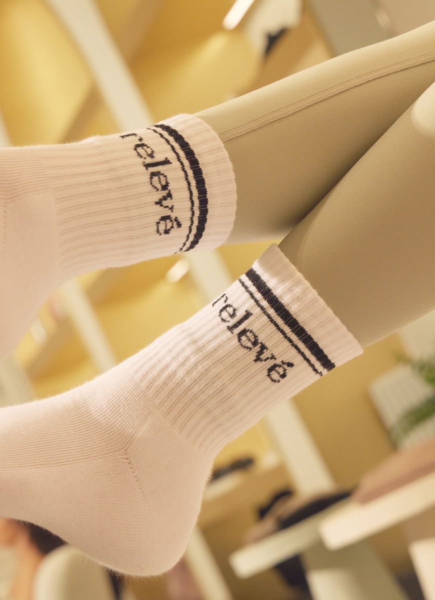 relevé Crew Socks in White with Black Logo Side View of Logo on Both Feet